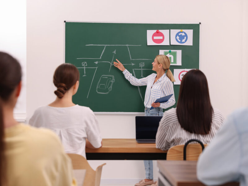 Teacher explaining traffic rules to audience during lesson in driving school